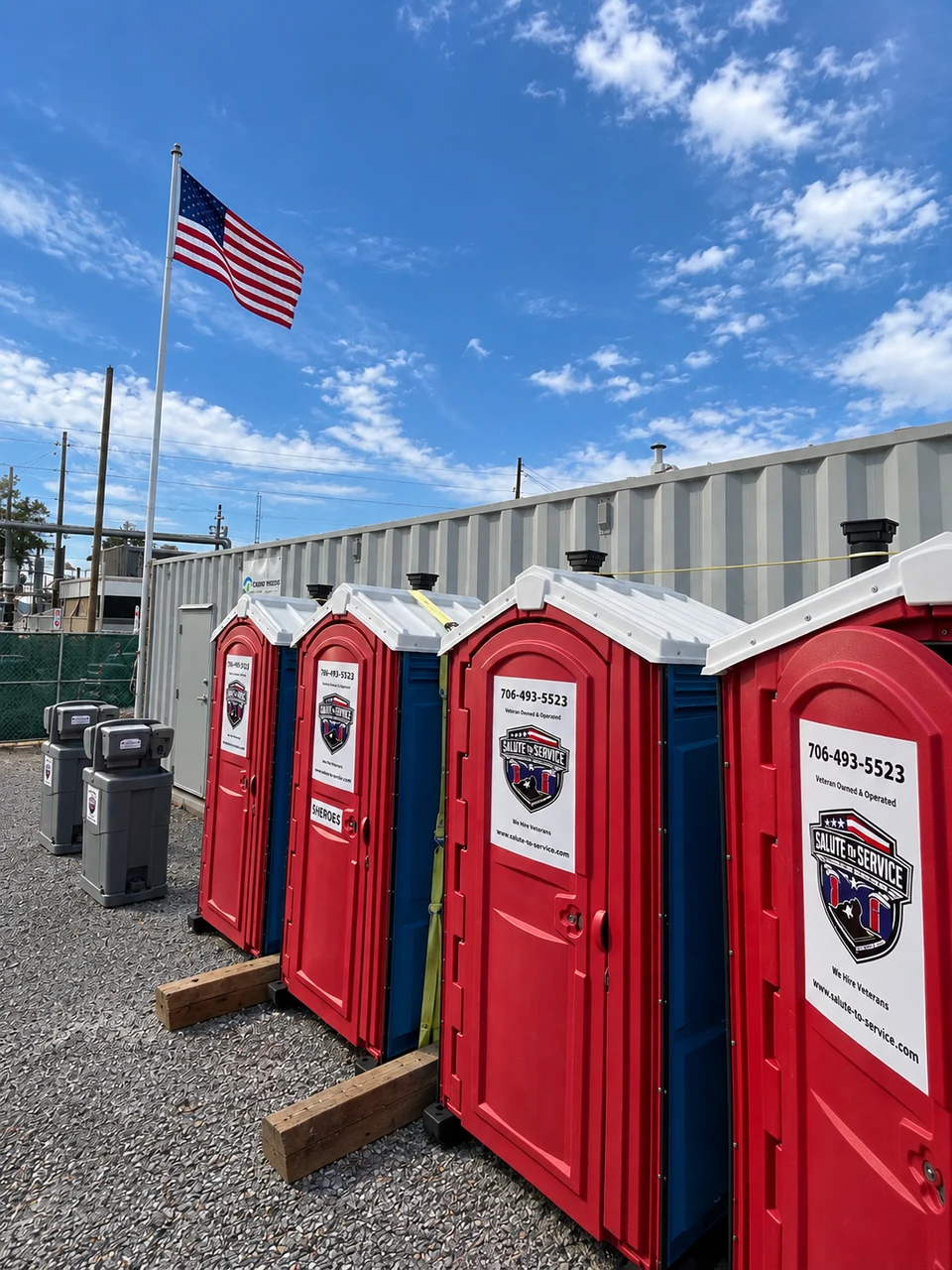 Authentic Salute To Service red and blue portable restrooms with an American flag.